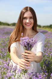 Young woman with lavender bouquet in field on summer day