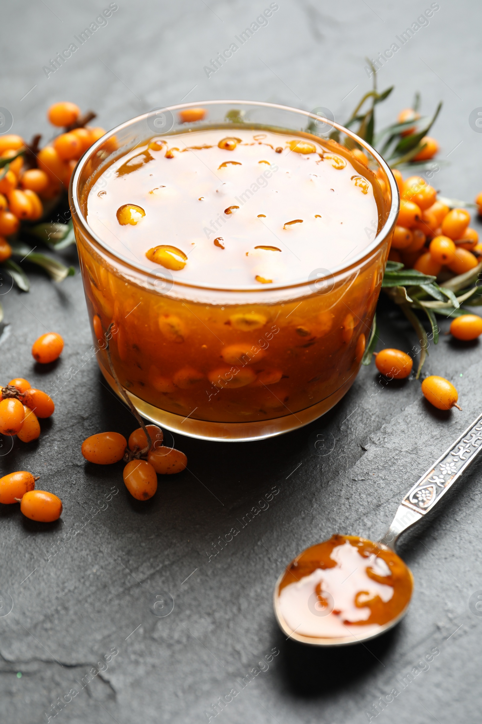 Photo of Delicious sea buckthorn jam and fresh berries on black table