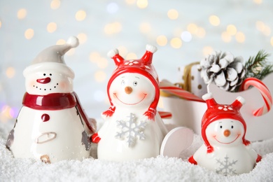 Photo of Christmas composition with decorative snowmen on artificial snow against blurred festive lights