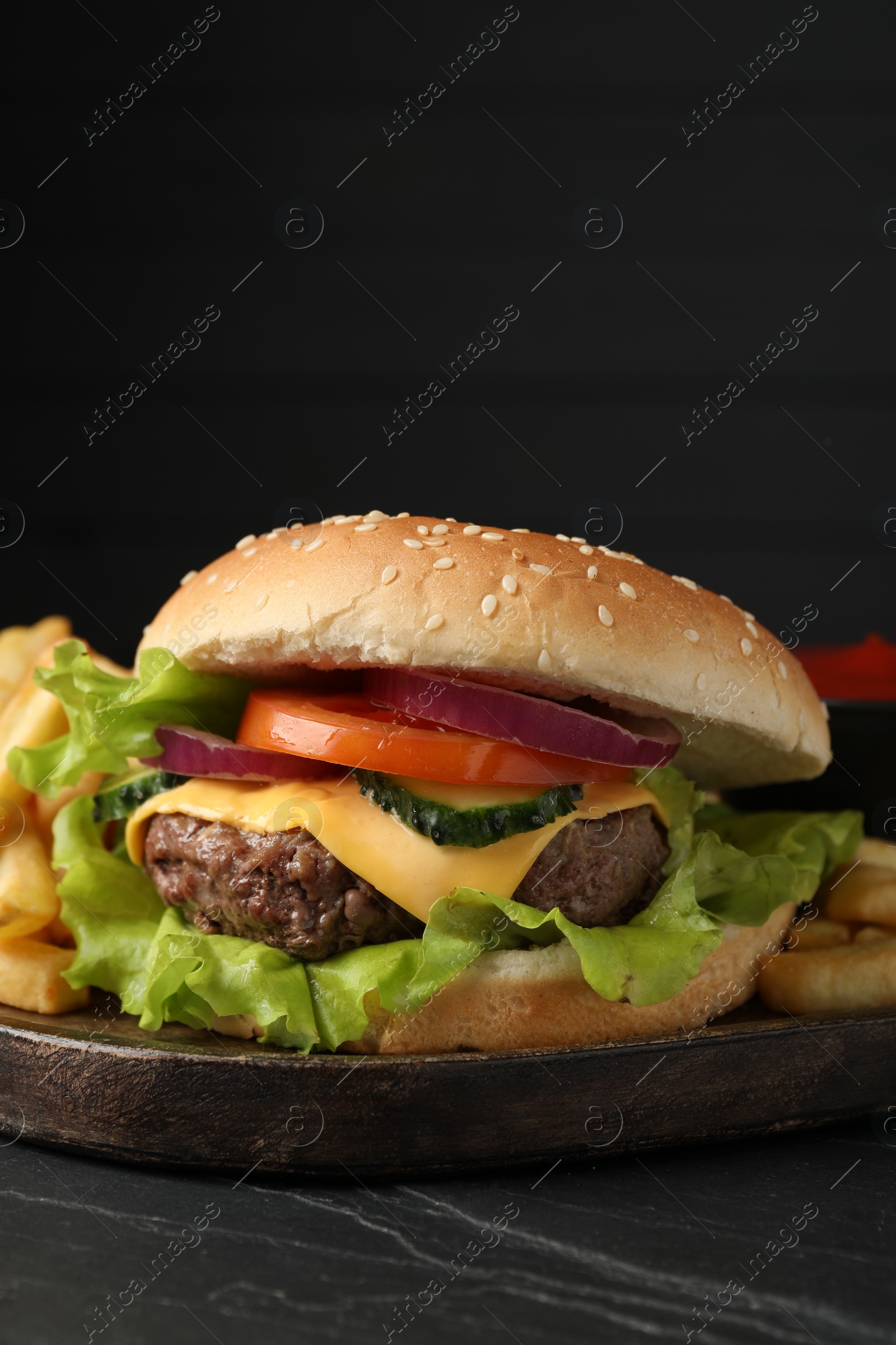 Photo of Delicious burger and french fries served on black table, closeup