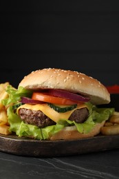 Photo of Delicious burger and french fries served on black table, closeup