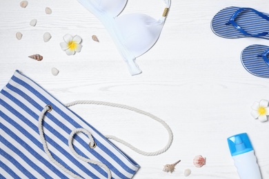 Flat lay composition with beach bag and accessories on white wooden background