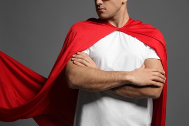 Man wearing superhero cape on grey background, closeup