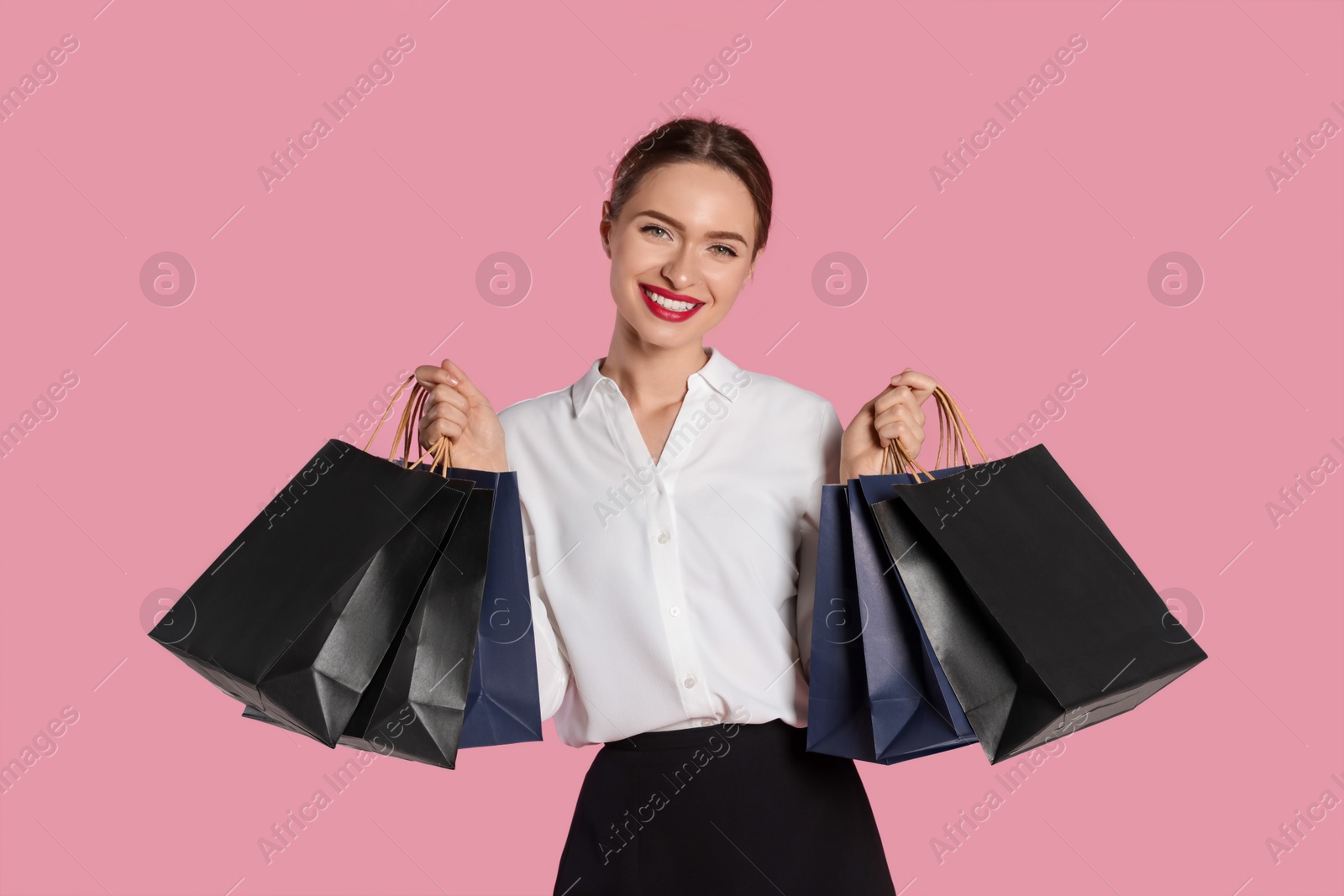 Photo of Happy young woman with shopping bags on light pink background. Big sale