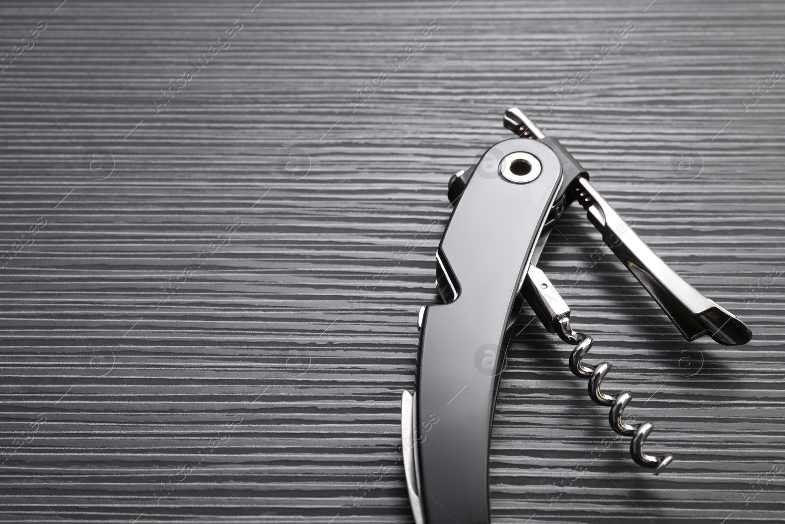 Photo of One corkscrew (sommelier knife) on black wooden table, top view. Space for text