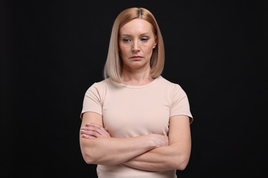 Photo of Portrait of sad woman with crossed arms on black background