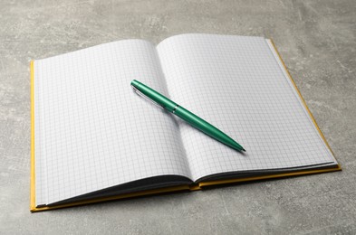 Photo of Open notebook and pen on grey table. Personal planning