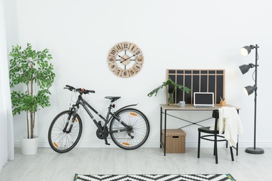 Photo of New bicycle near wall in stylish room interior