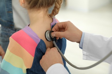 Photo of Mother and daughter having appointment with doctor. Pediatrician examining patient with stethoscope indoors, closeup