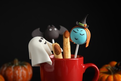 Photo of Different cake pops in cup decorated as monsters, closeup. Halloween treat