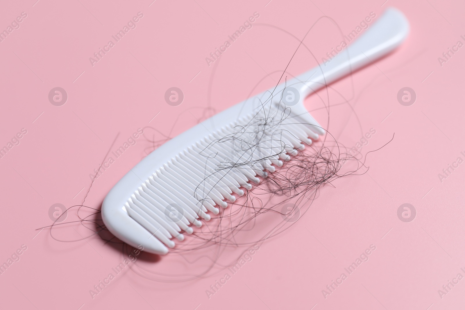 Photo of Comb with lost hair on pink background