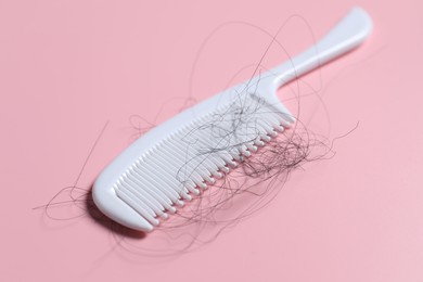 Photo of Comb with lost hair on pink background