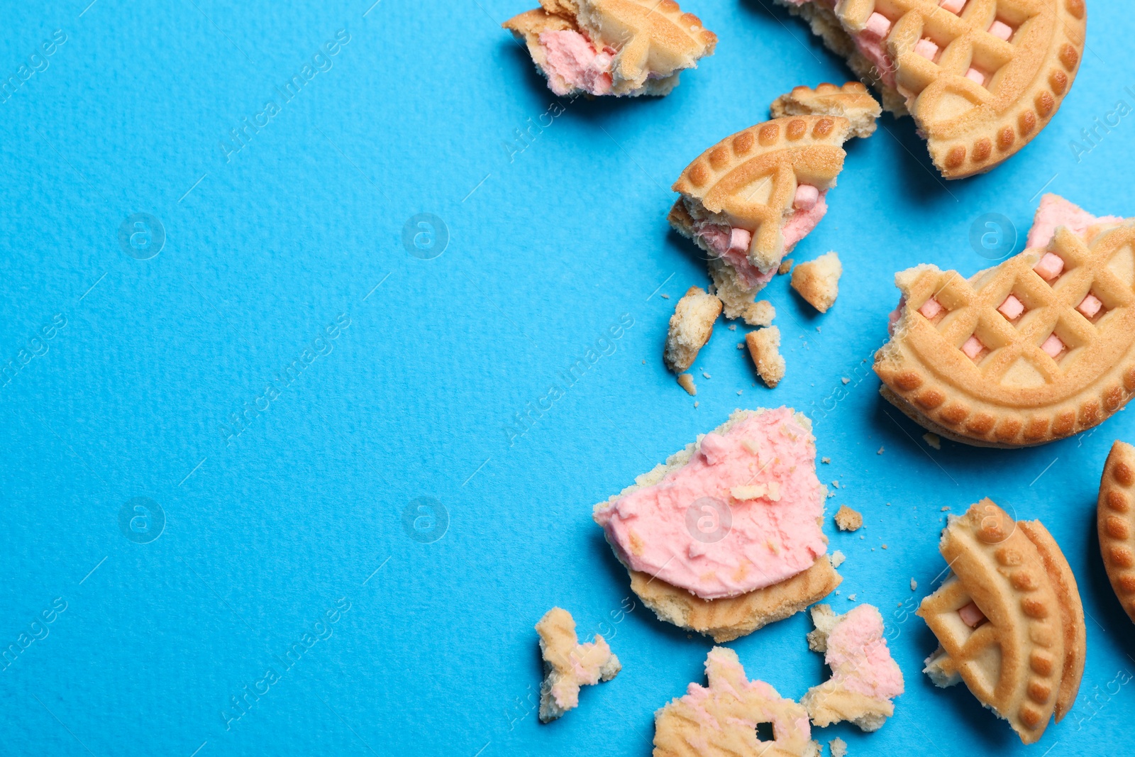 Photo of Tasty sandwich cookies with cream on light blue background, flat lay. Space for text