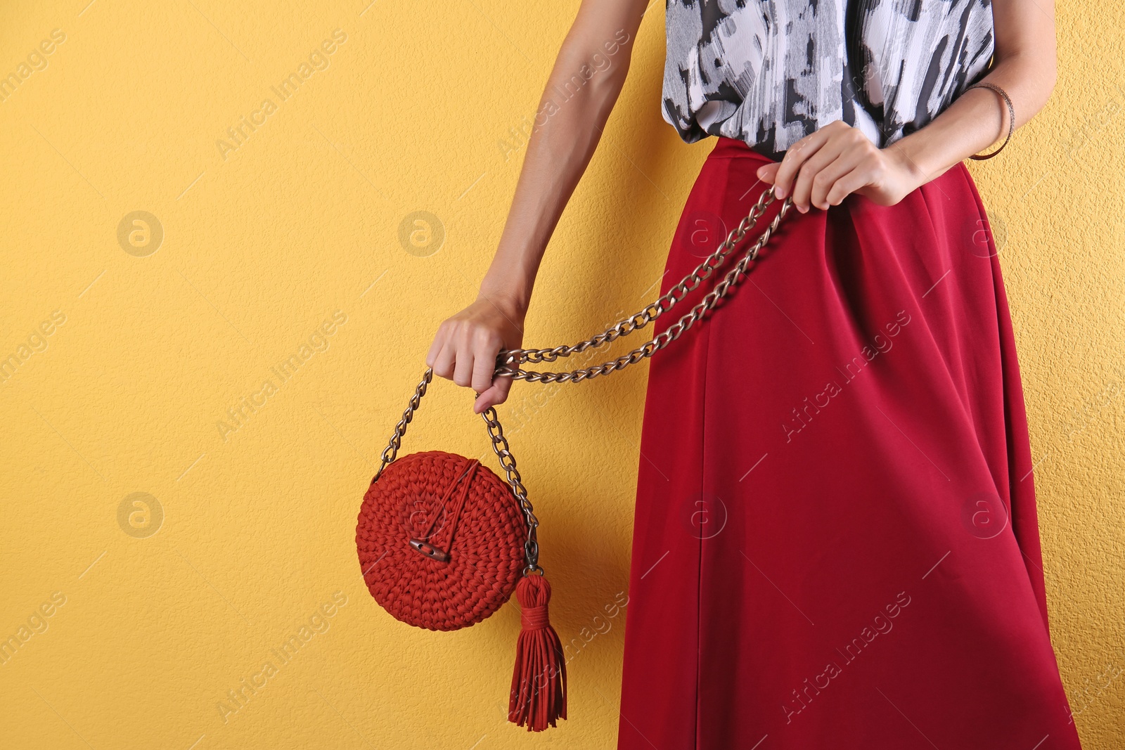 Photo of Young woman in stylish outfit with purse on color background, closeup