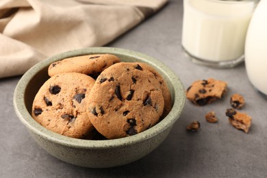 Photo of Delicious chocolate chip cookies and milk on grey table