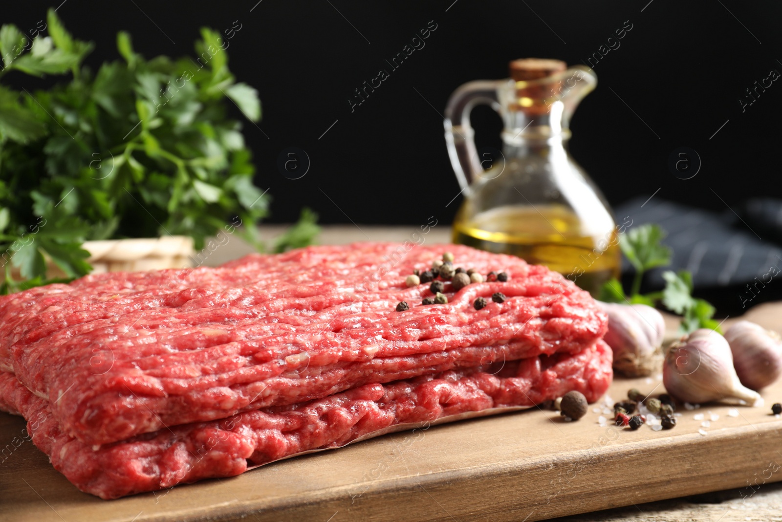 Photo of Raw ground meat, spices, parsley and oil on table, closeup