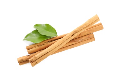 Photo of Aromatic dry cinnamon sticks and green leaves on white background, top view
