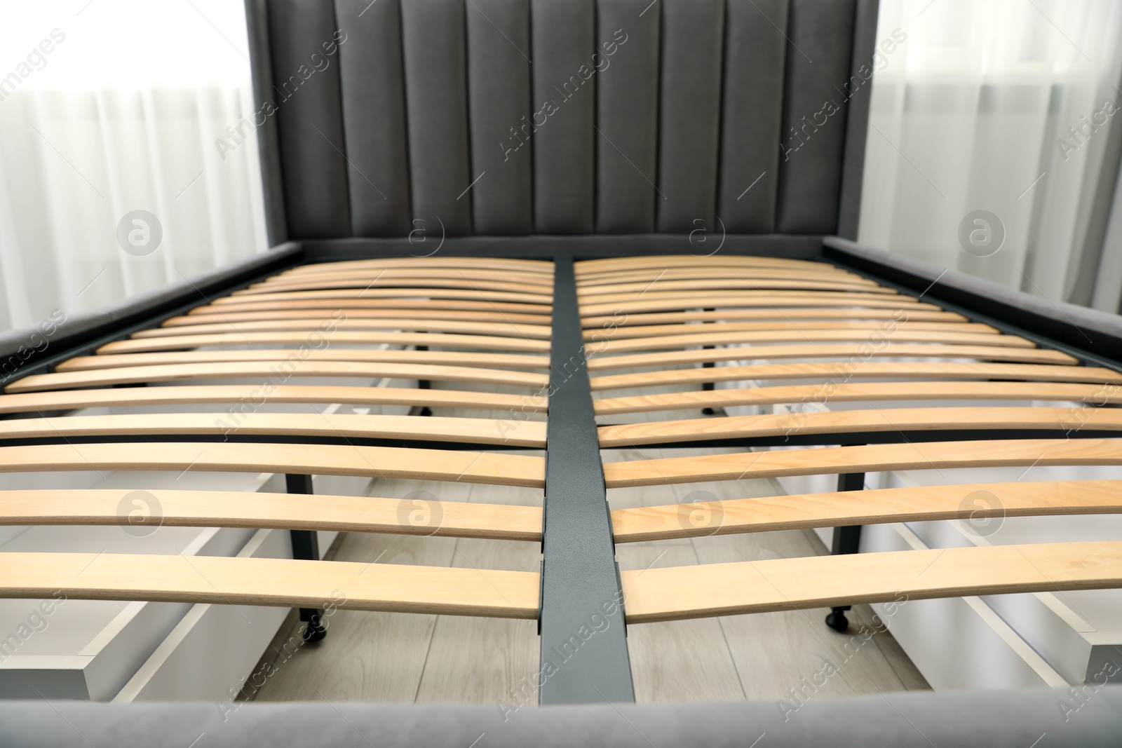 Photo of Modern bed with storage space for bedding under slatted base in room, closeup