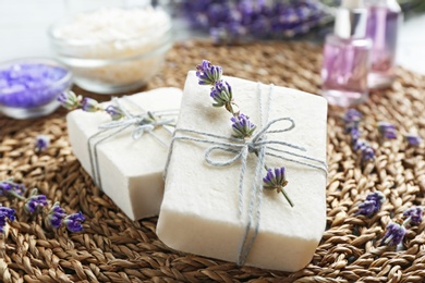 Handmade soap bars with lavender flowers on wicker mat, closeup
