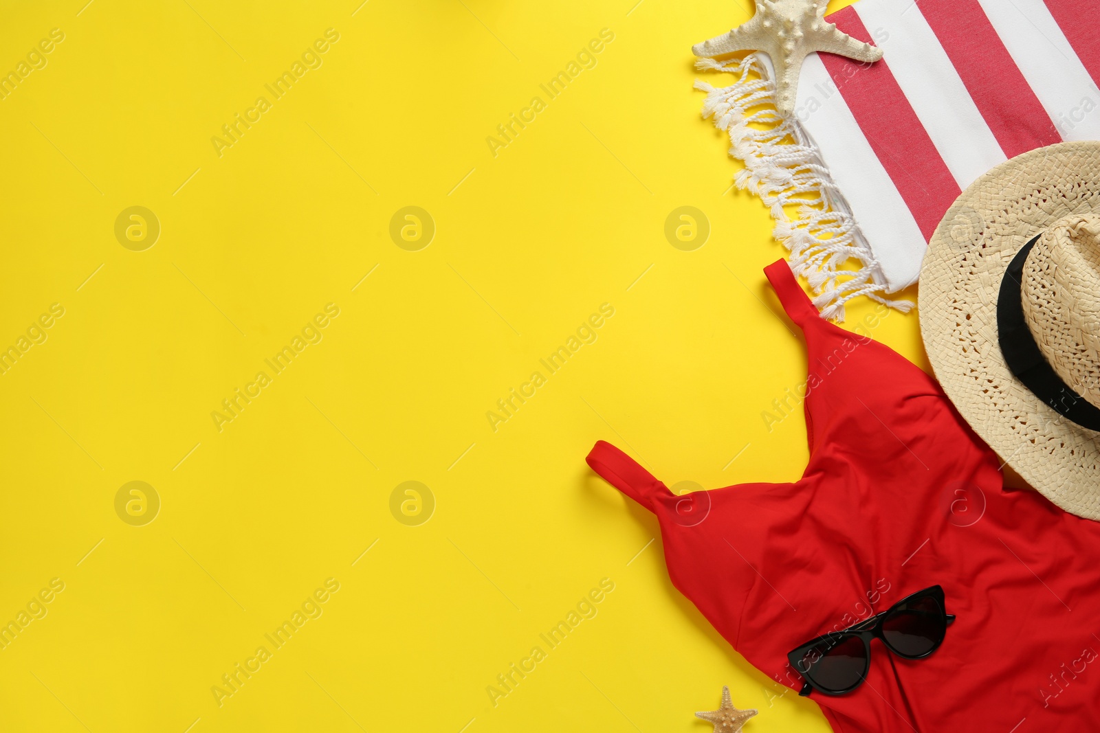 Photo of Beach towel, swimsuit, straw hat and sunglasses on yellow background, flat lay. Space for text