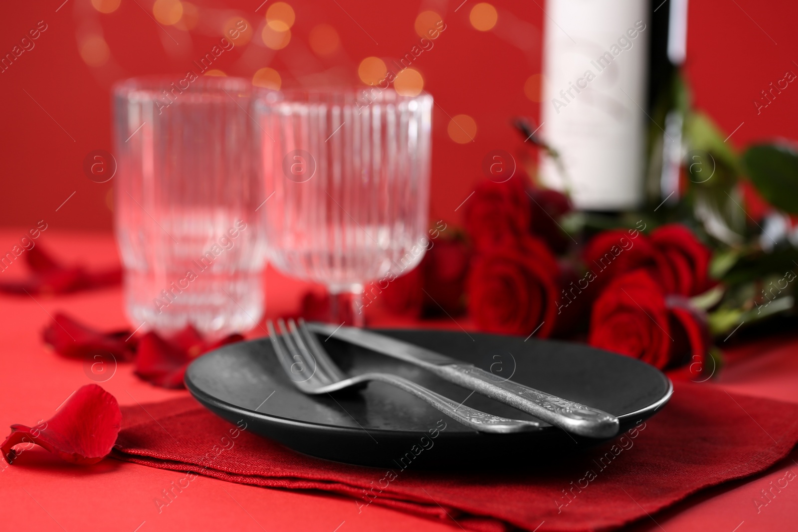 Photo of Place setting with roses on red table, closeup. Romantic dinner