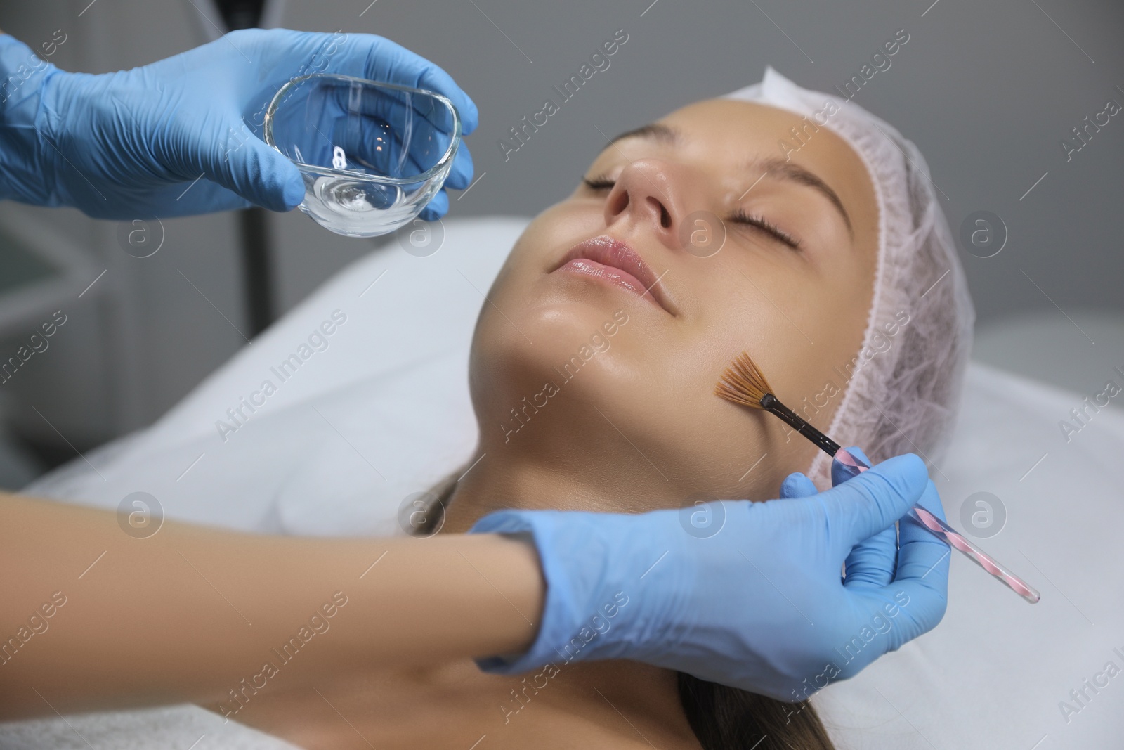 Photo of Cosmetologist applying chemical peel product on client's face in salon