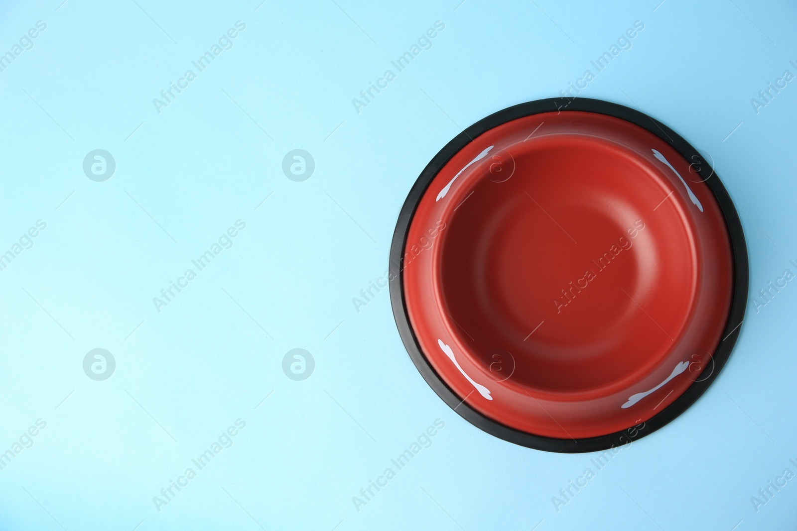 Photo of Empty red feeding bowl on light blue background, top view. Space for text