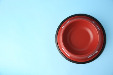 Empty red feeding bowl on light blue background, top view. Space for text