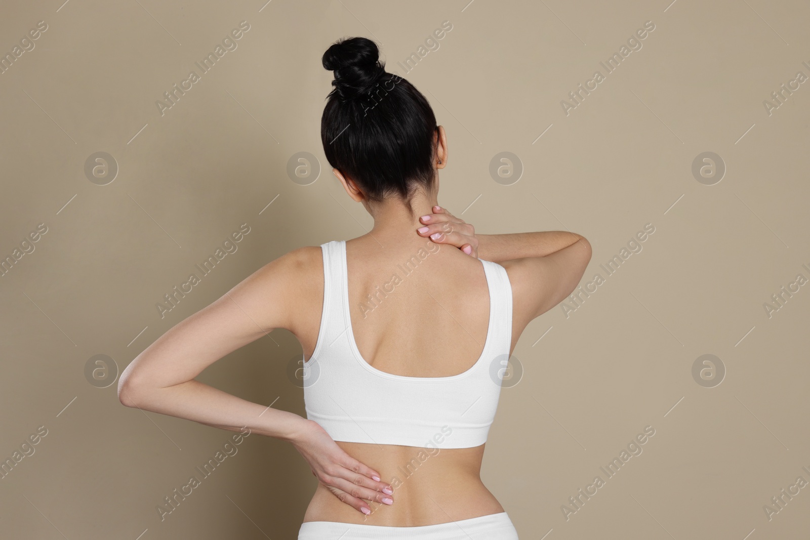 Photo of Woman suffering from pain in back on beige background