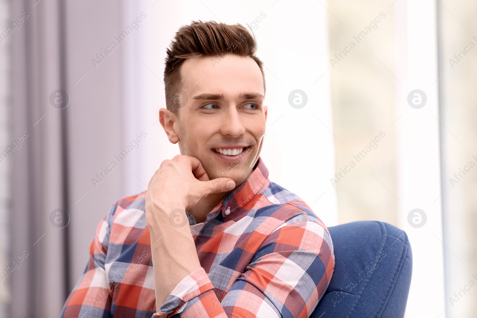 Photo of Young man sitting in armchair at home