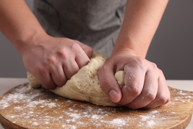 Man kneading dough at table near grey wall, closeup