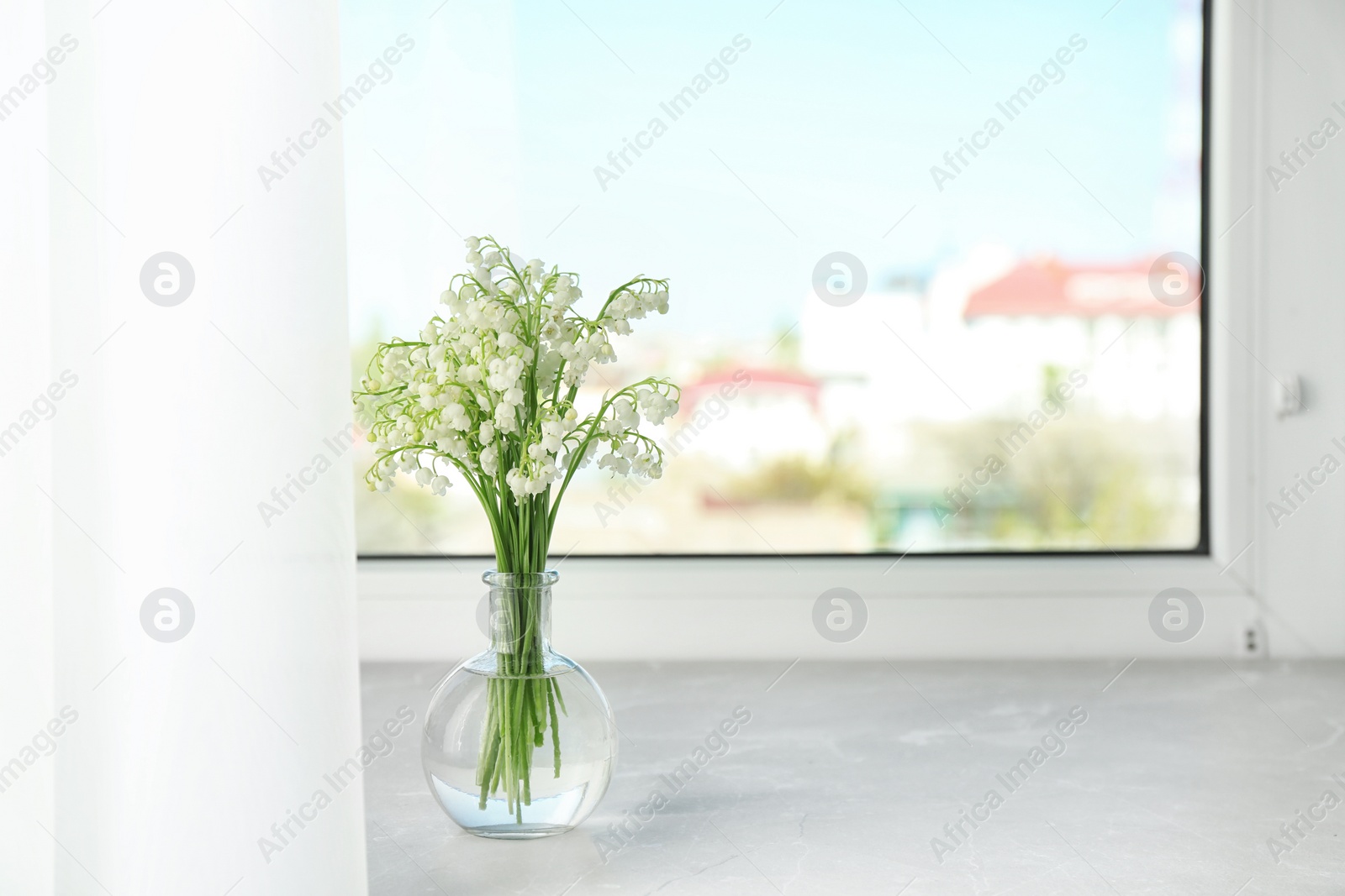 Photo of Beautiful lily of the valley bouquet in vase on windowsill, space for text