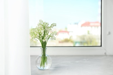 Beautiful lily of the valley bouquet in vase on windowsill, space for text