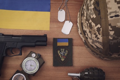 Photo of MYKOLAIV, UKRAINE - SEPTEMBER 26, 2020: Tactical gear and Ukrainian flag on  table, flat lay