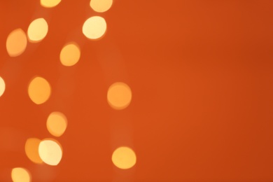 Photo of Beautiful blurred lights on orange background, bokeh effect. Space for text
