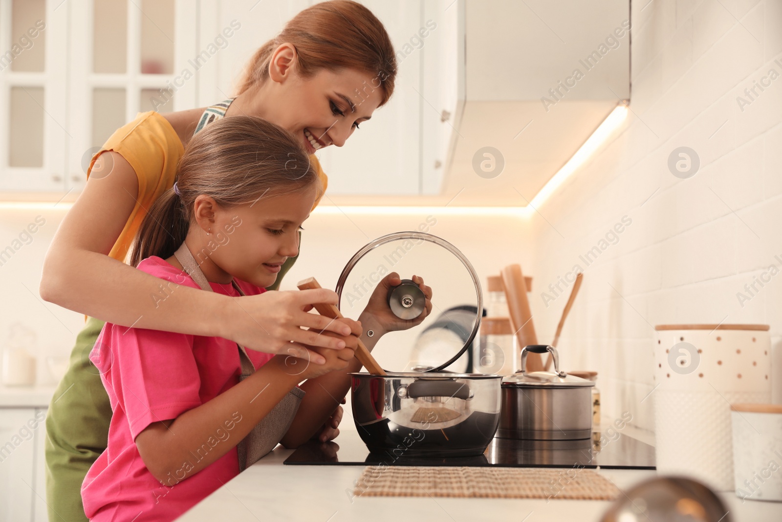 Photo of Mother and daughter cooking together in kitchen