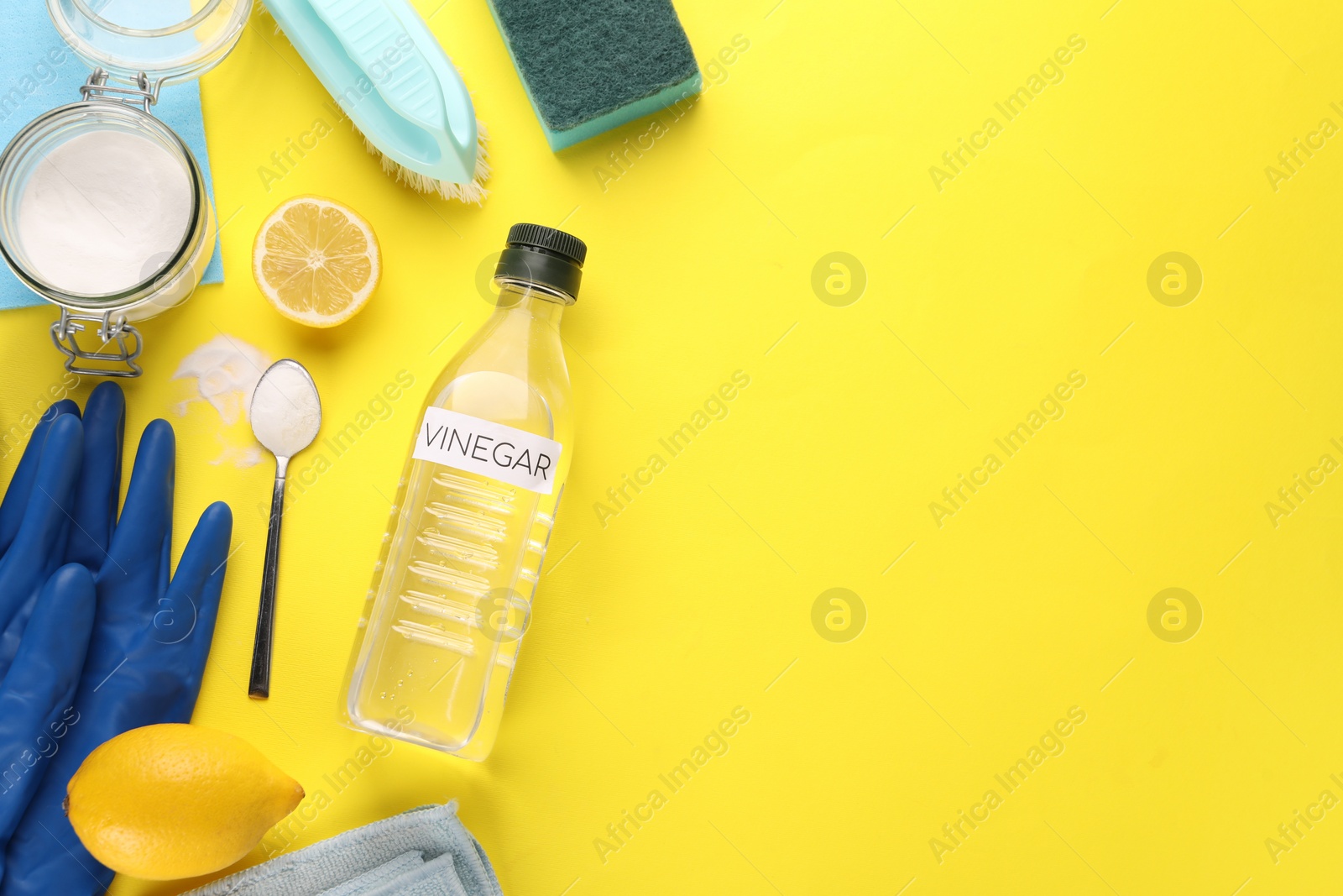 Photo of Eco friendly natural cleaners. Flat lay composition with bottle of vinegar on yellow background, space for text