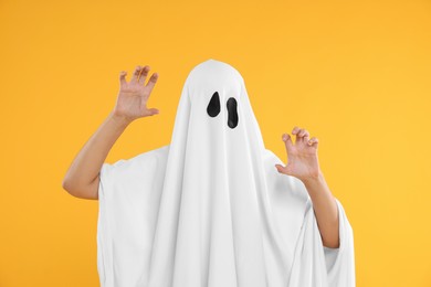 Photo of Woman in white ghost costume on yellow background. Halloween celebration