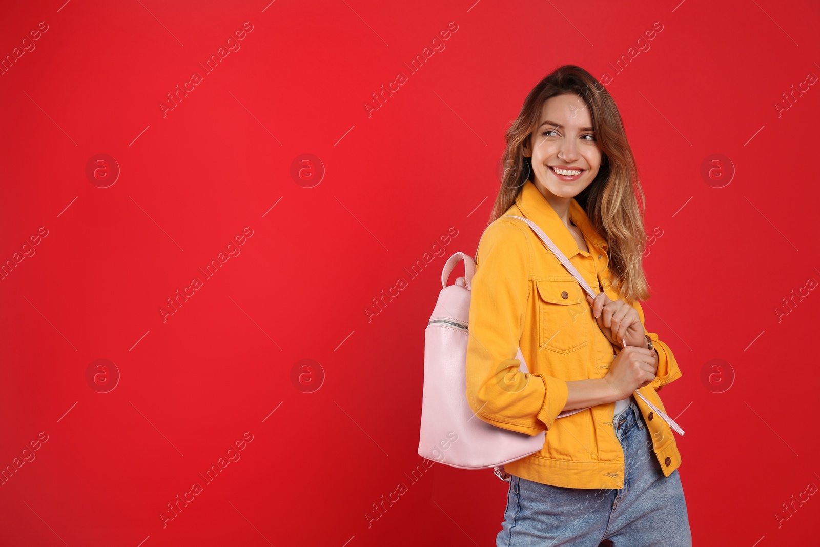 Photo of Happy woman with backpack on red background. Space for text