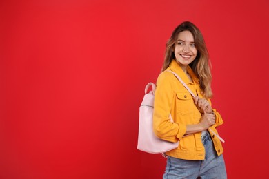 Happy woman with backpack on red background. Space for text