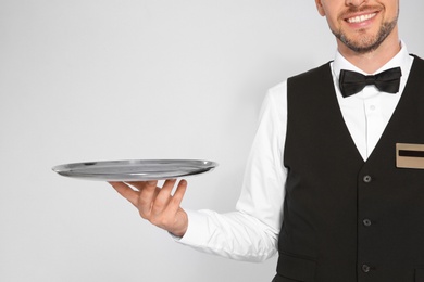 Photo of Young waiter with empty tray on light background