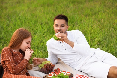 Happy young couple having picnic in green park