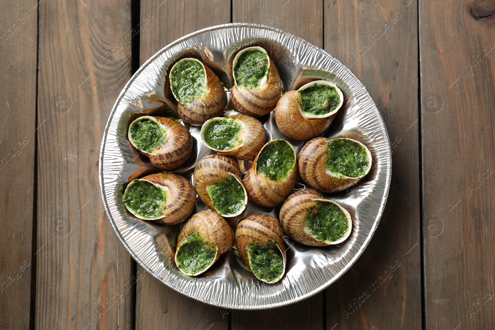 Photo of Delicious cooked snails on wooden table, top view