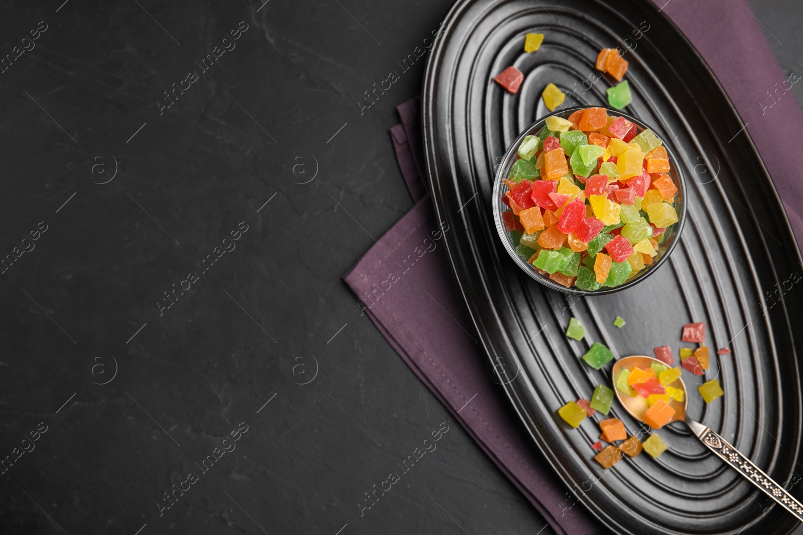 Photo of Mix of delicious candied fruits on black table, flat lay. Space for text