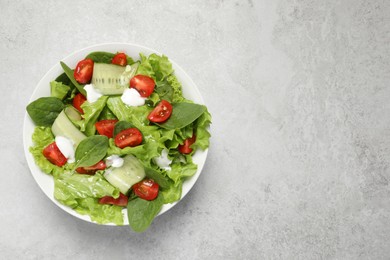 Photo of Delicious vegetable salad on light grey table, top view. Space for text