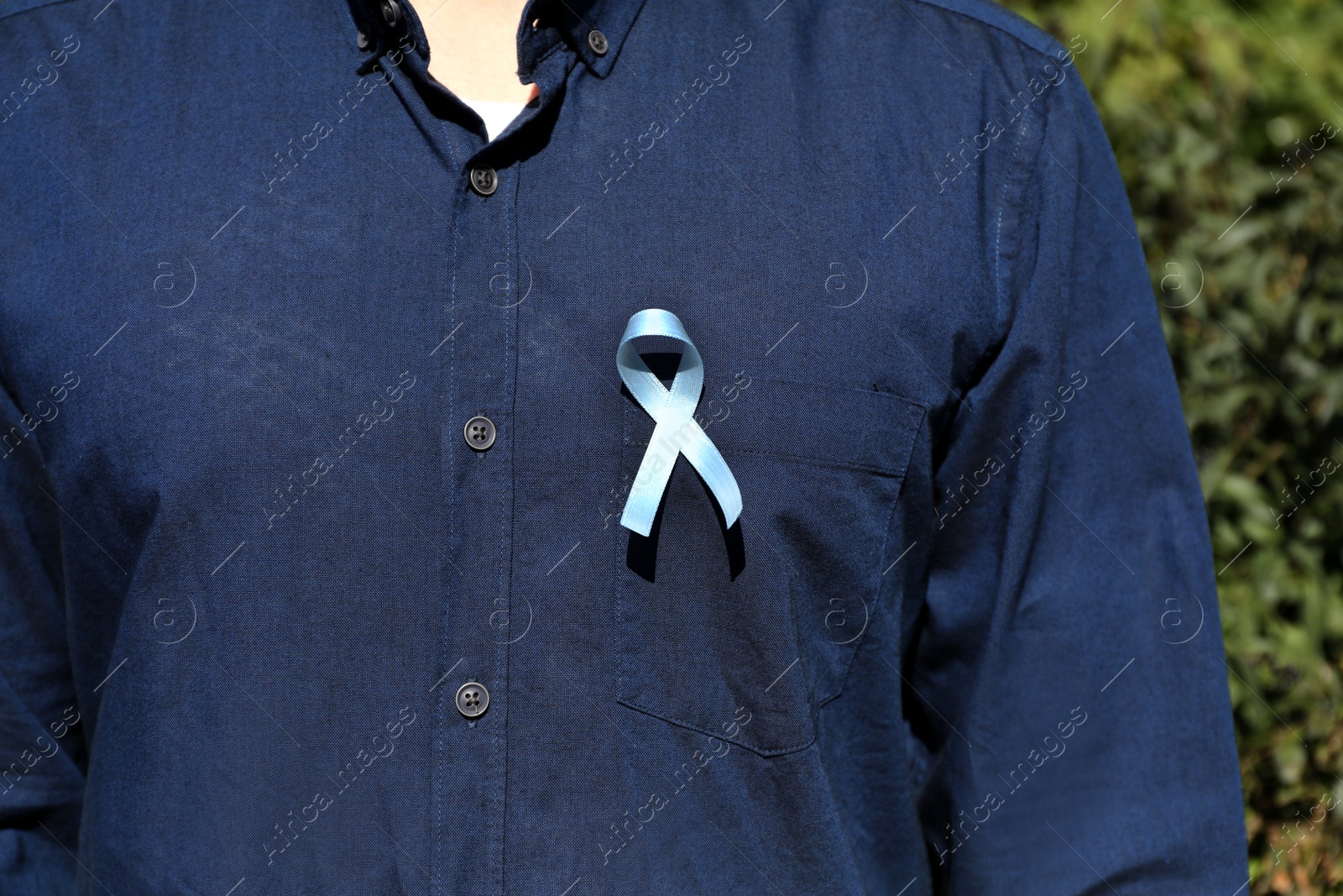 Photo of Man with light blue ribbon outdoors, closeup. World Diabetes Day