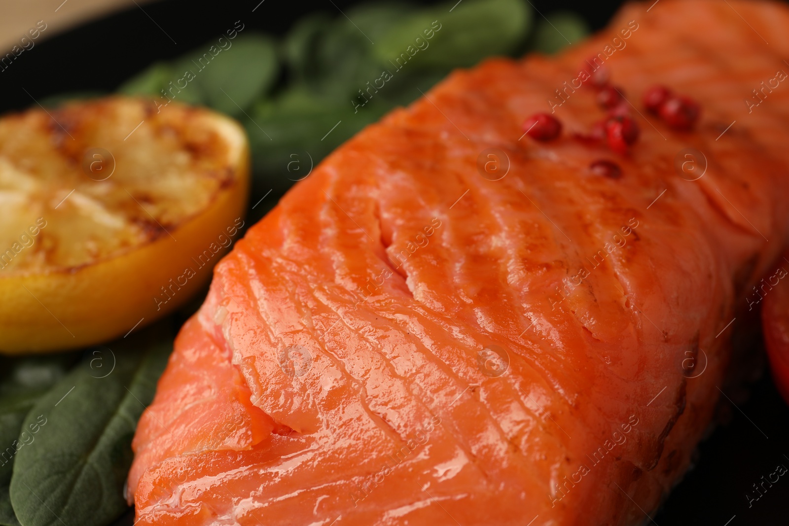 Photo of Tasty grilled salmon with lemon and basil, closeup