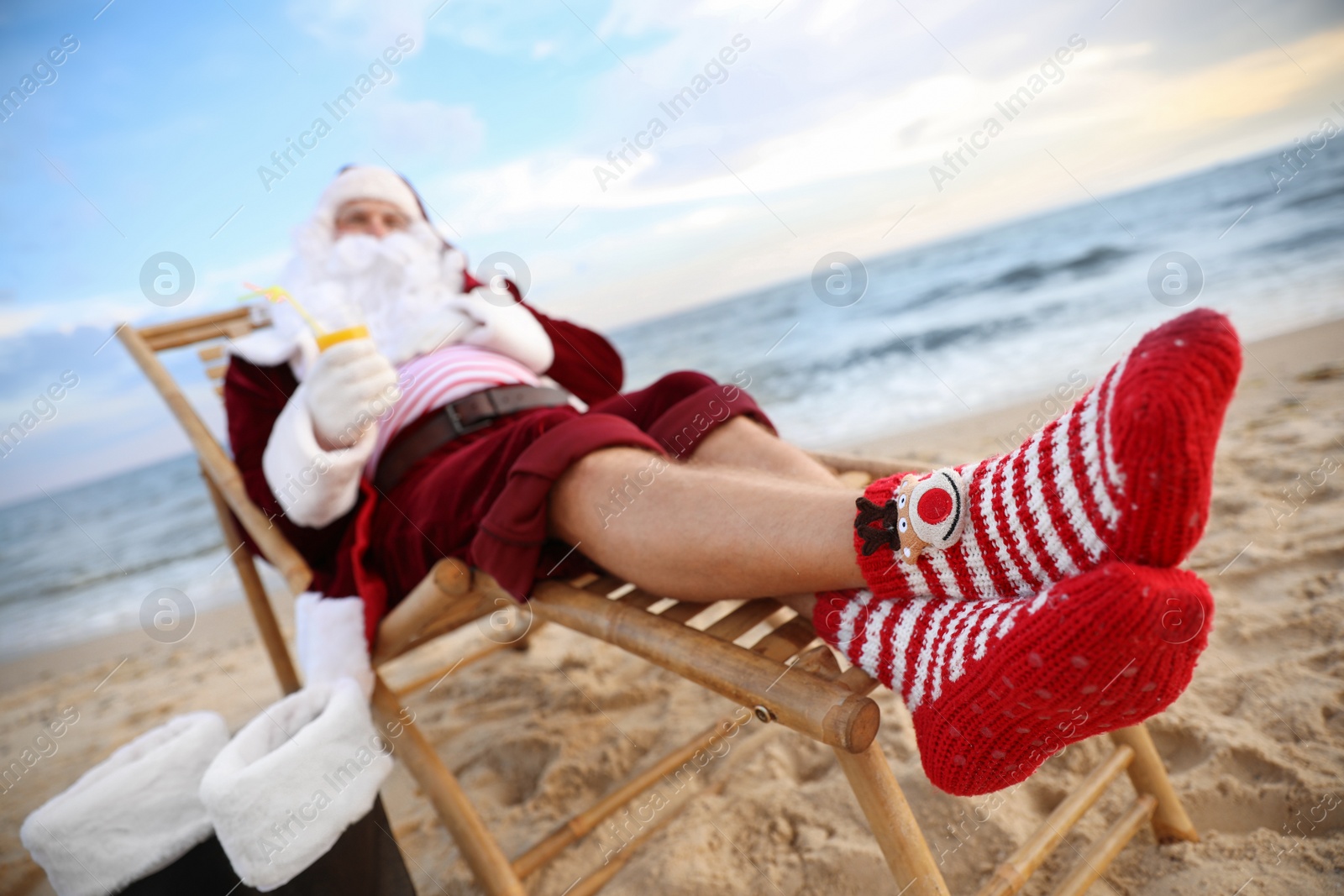 Photo of Santa Claus relaxing on beach. Christmas vacation