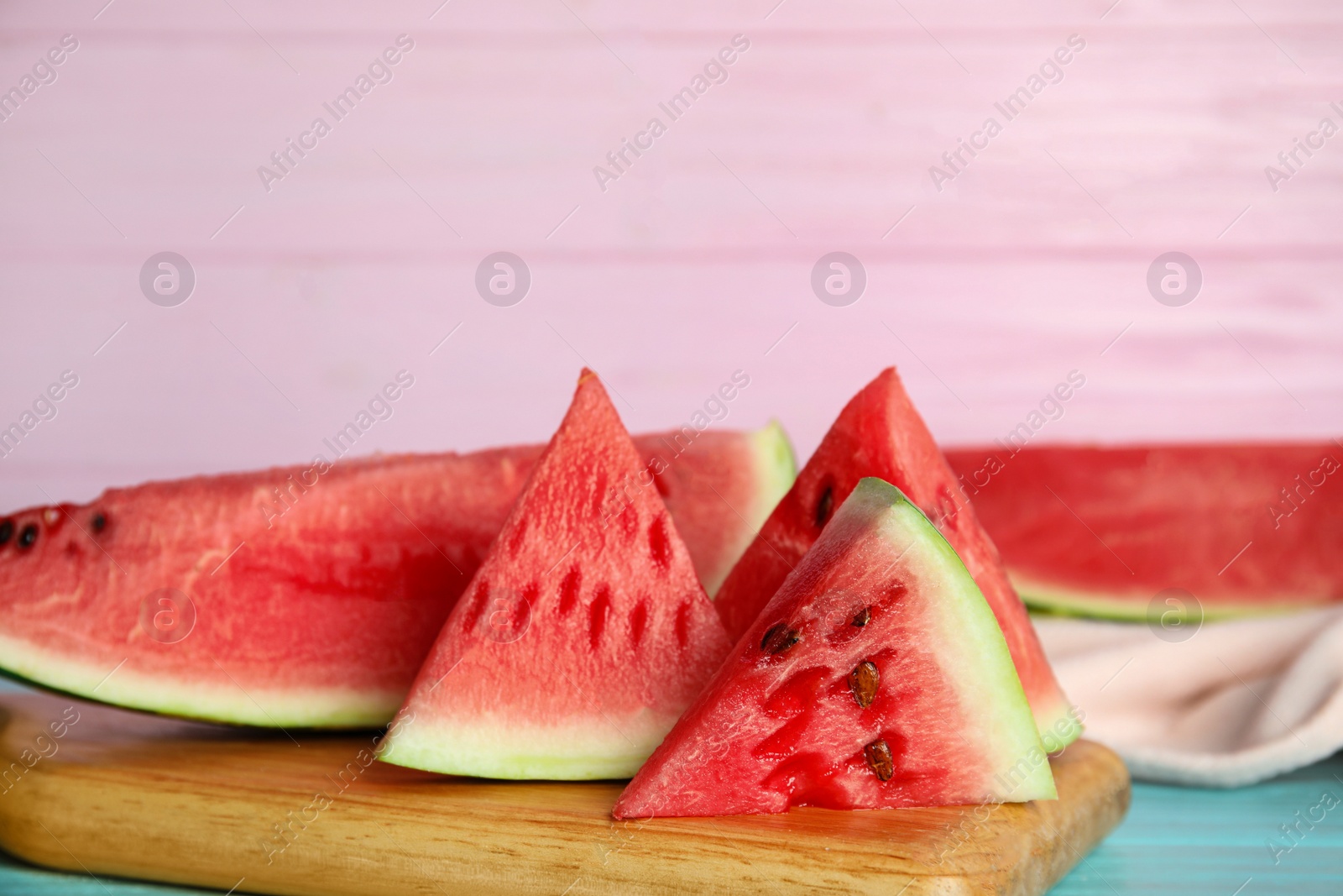 Photo of Yummy watermelon slices on wooden board near pink wall