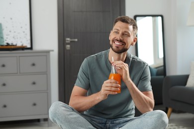 Man holding bottle of delicious juice at home